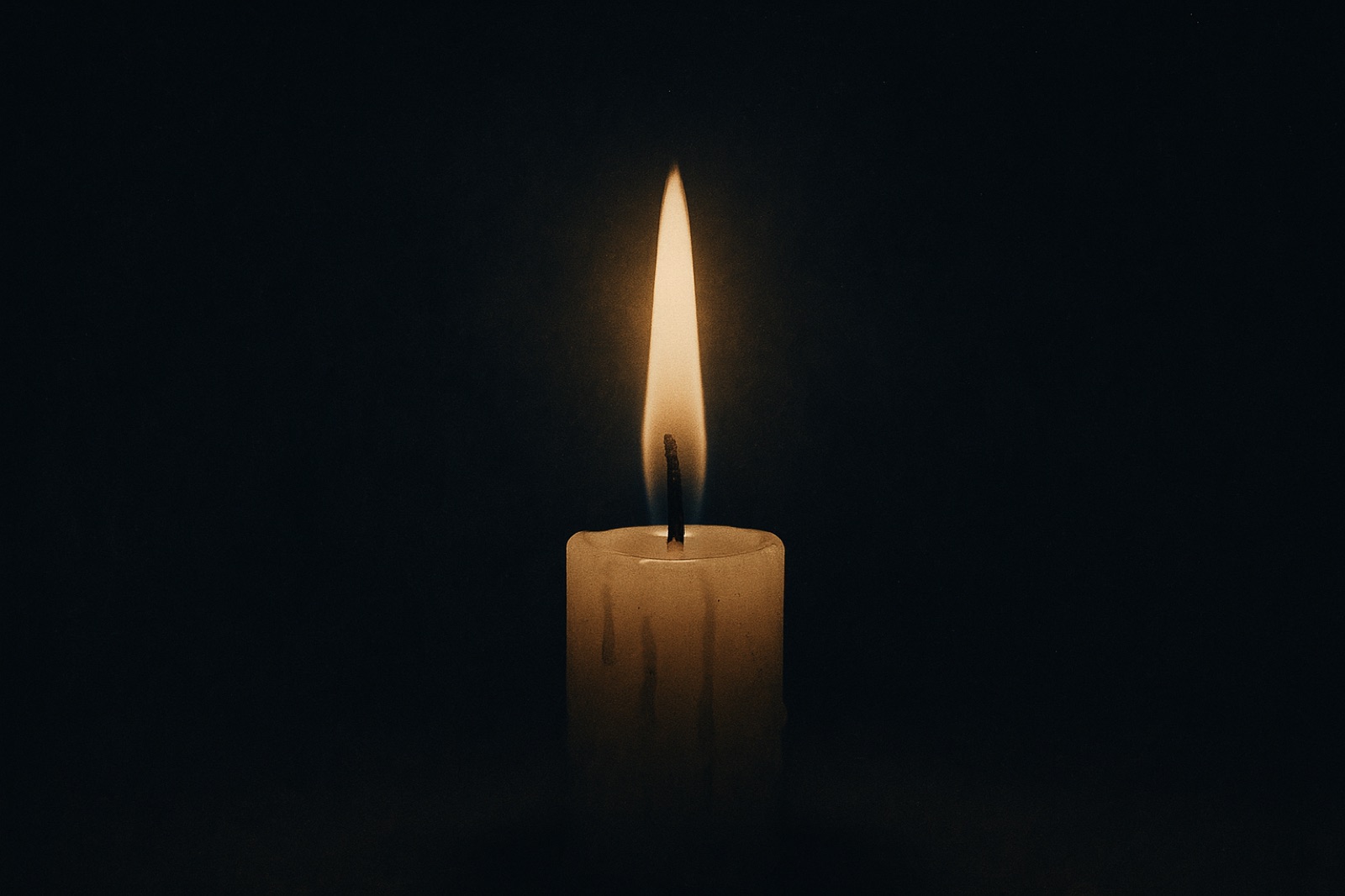 A solitary candle flame against a plain black backdrop, epitomizing simplicity and tranquility.